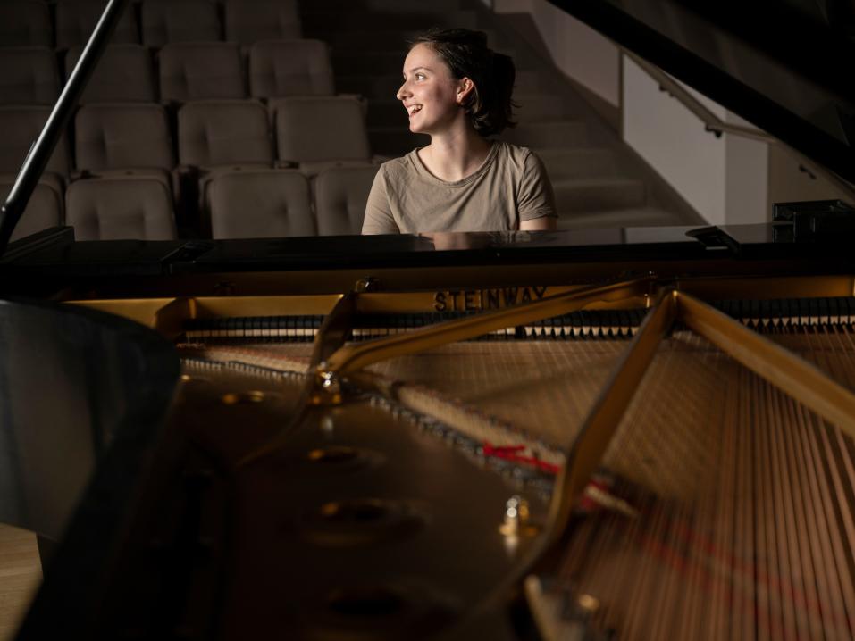 A student sits at a grand piano.