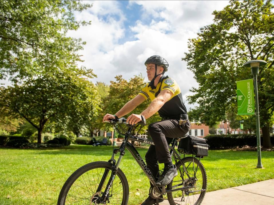 A student security officer patrols campus on a bicycle.