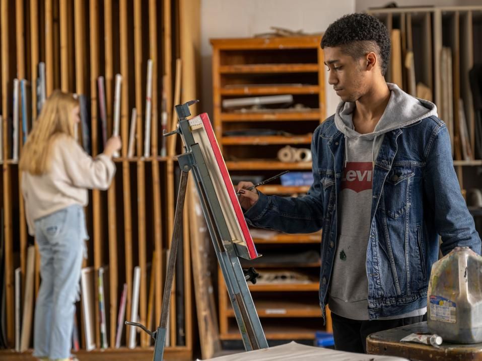 Two students painting in one of the arts studios on campus.