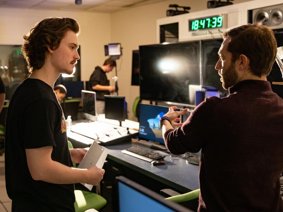 student and faculty member talking in a film production room 