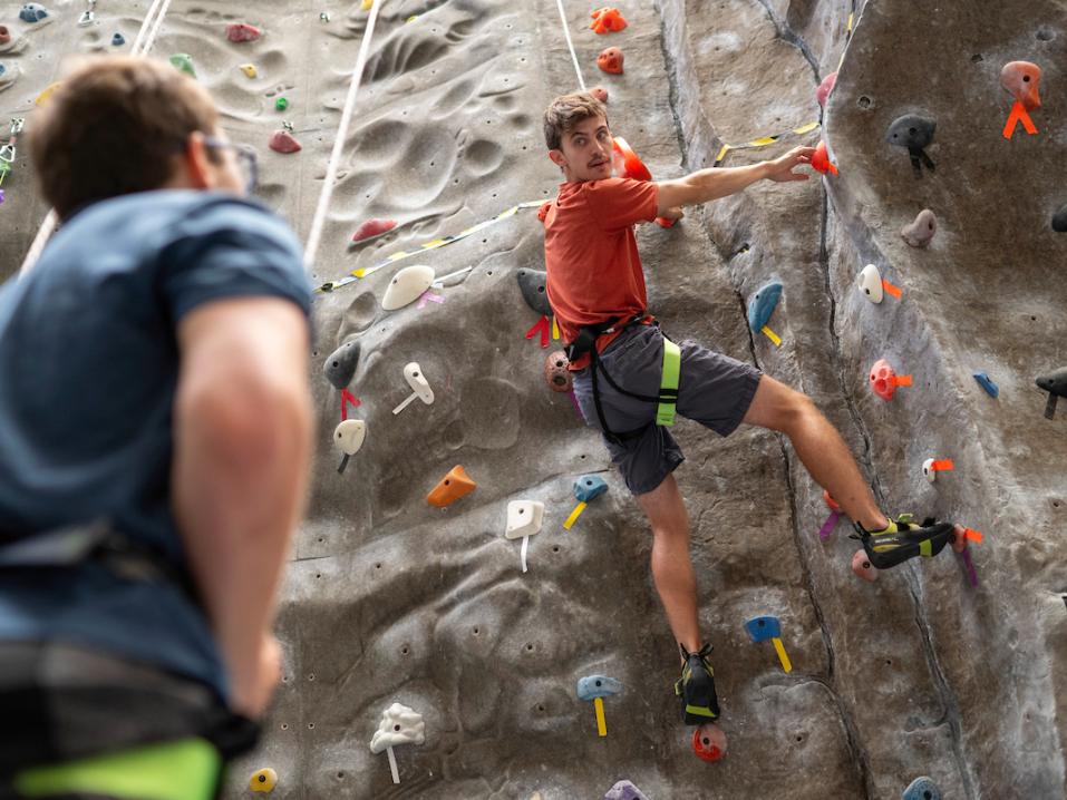 student rock climbing with a spotter