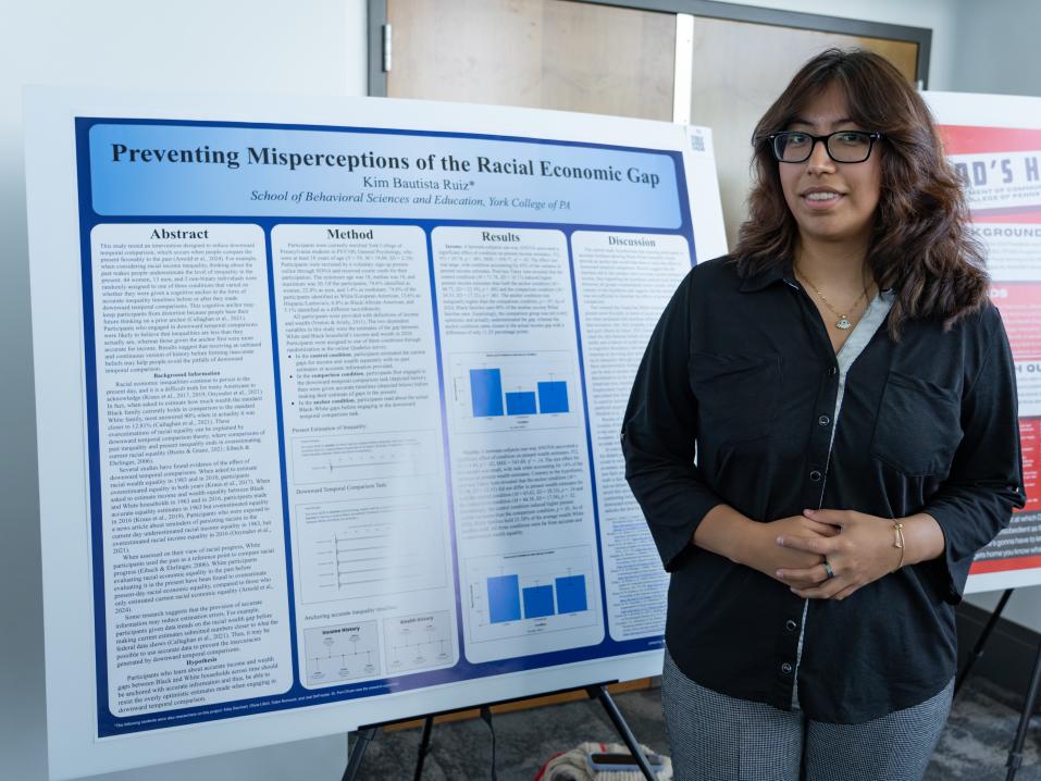 Kimberly Bautista Ruiz stands next to her presentation at the Undergraduate Research Showcase
