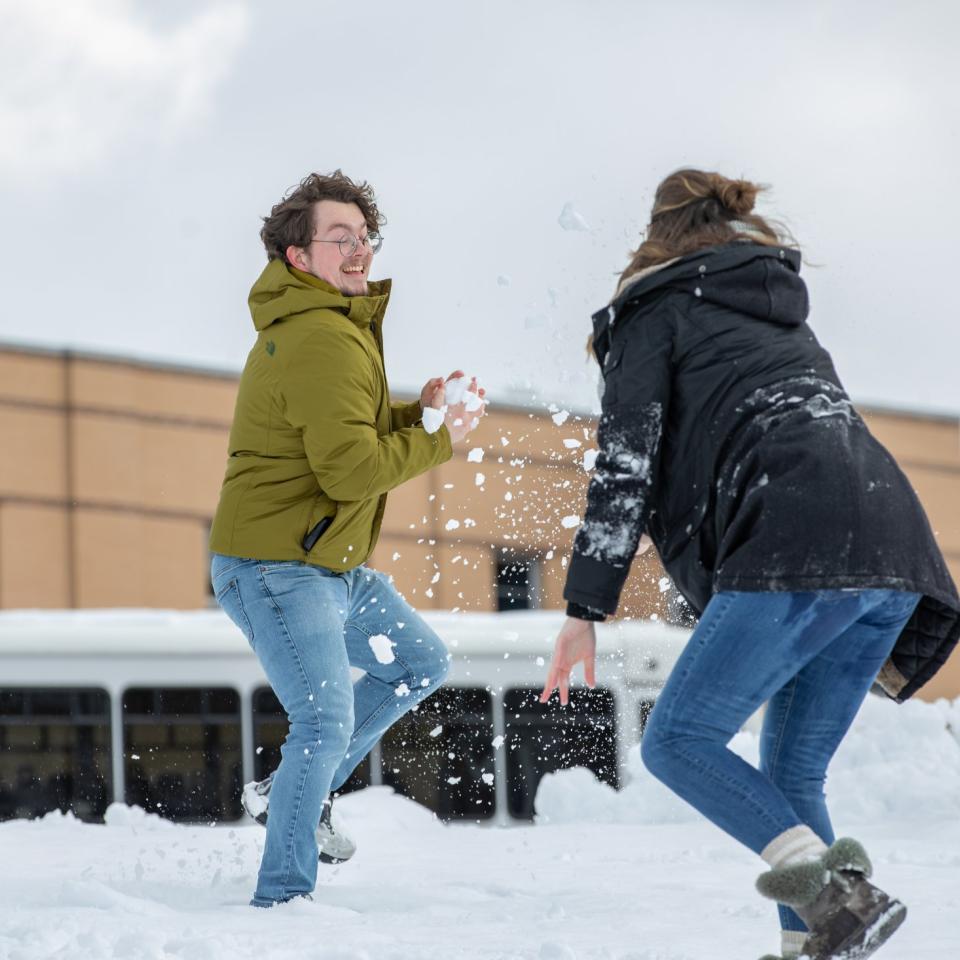 Two students have a snowball fight on campus