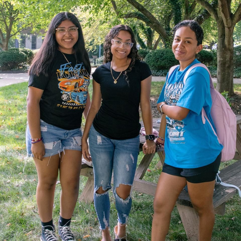 Three students pose together outdoors on campus on the first day of classes