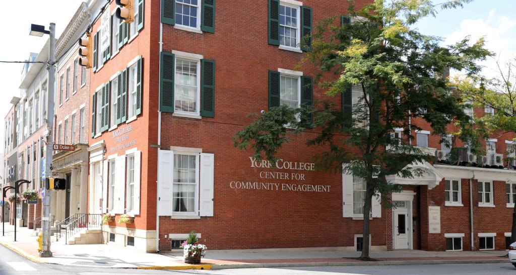 The brick front of a building shows colonial-style architecture and a sign reading "York College of Pennsylvania Center for Community Engagement."