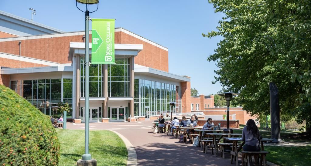 Outside view of the Waldner Performing Arts Center with students sitting at tables along the walkway