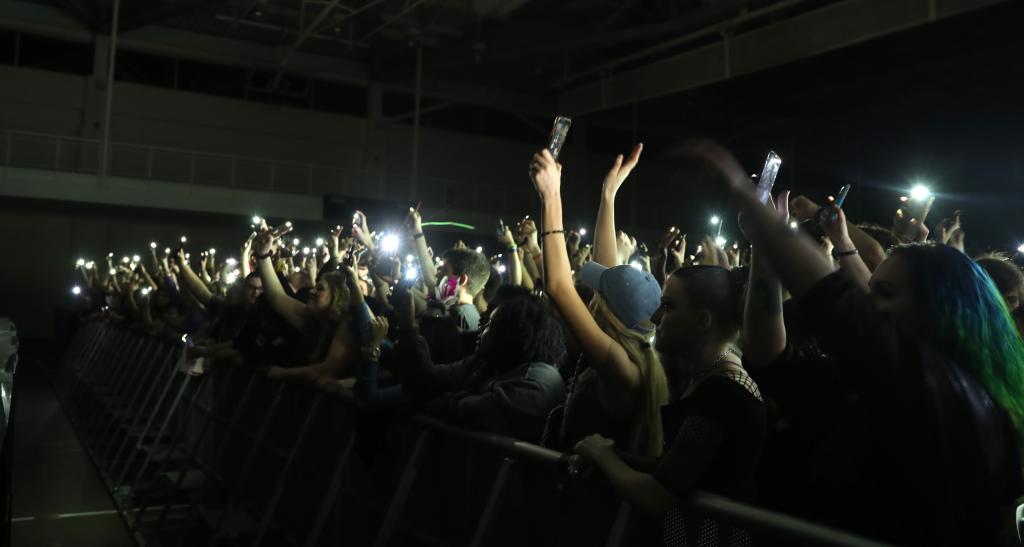 Cheering fans holding up cell phones with flashlight on at the Steve Aoki concert.