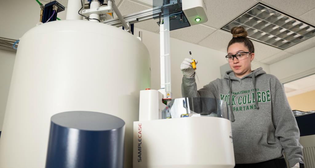 A student works with a large machine in the chemistry lab