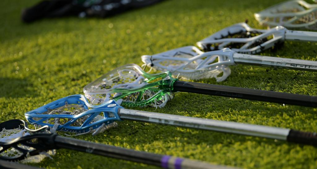 Lacrosse sticks lined up on the ground.