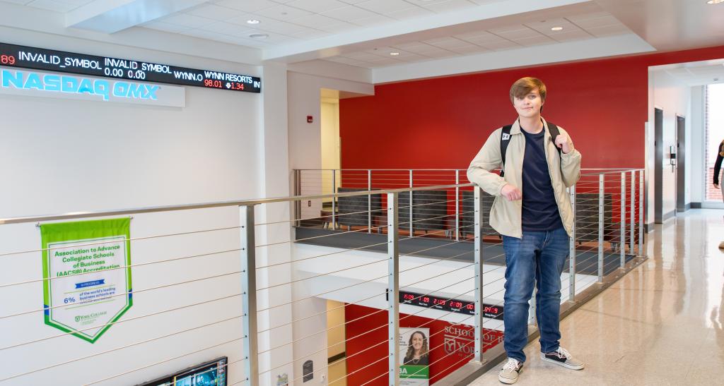 Student standing at railing on the second level of the Graham School of Business