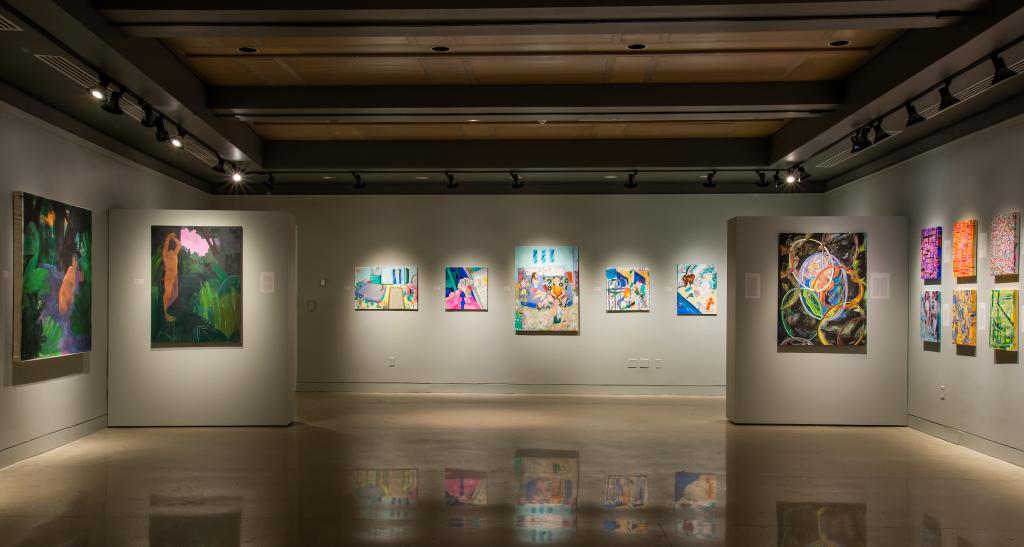 Framed works of art are hung on a gallery wall. 