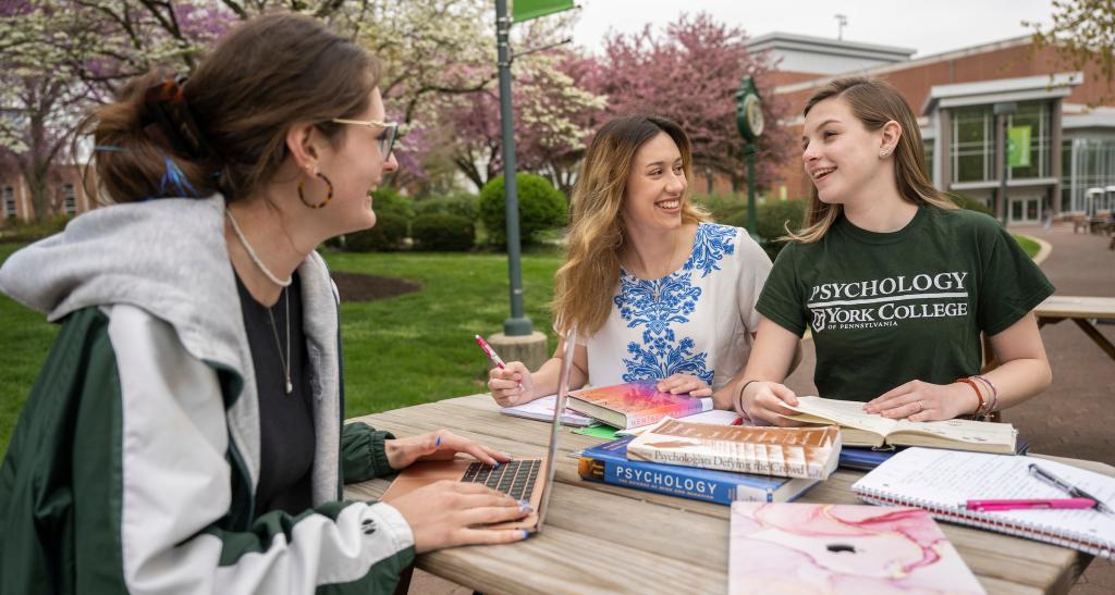 Psychology students talking at a table outside.