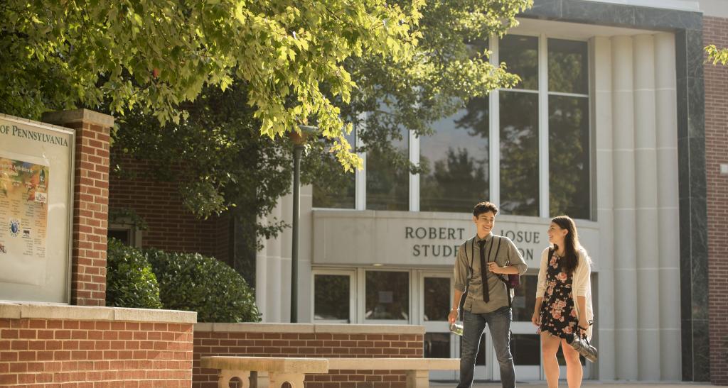 Two students walk together in front of the Iosue Student Union building