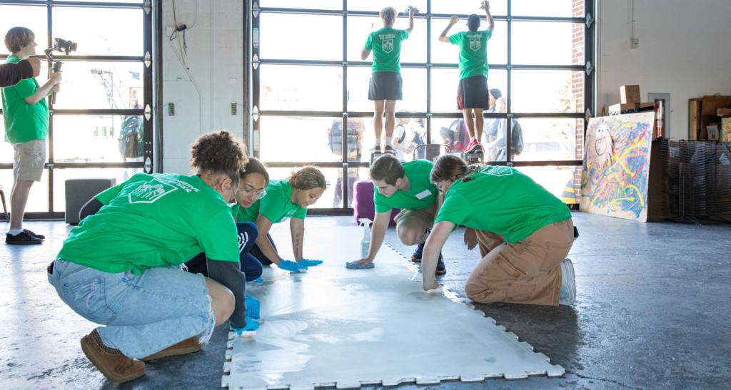 Students in Green Spartan Serve t-shirts clean floors and walls of Keystone Kid Space