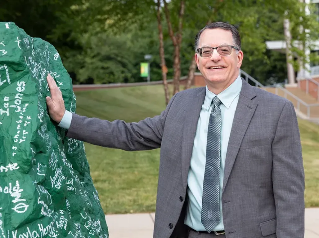 President Burns standing next to rock