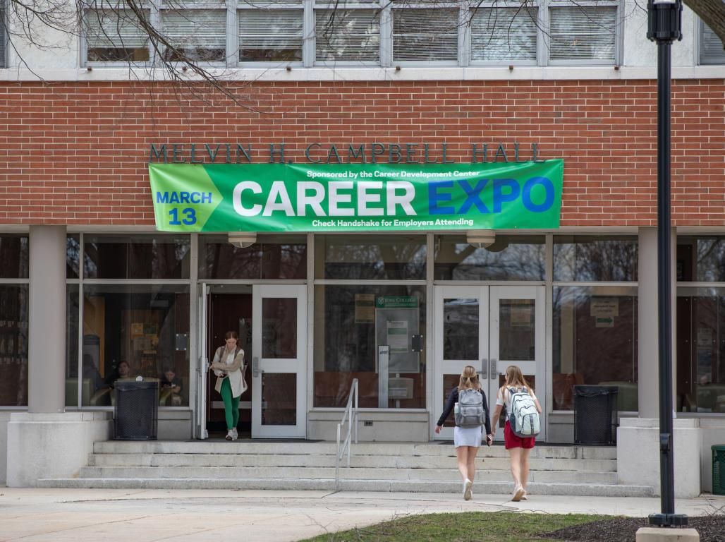 Two students walking to Campbell Hall, one student is walking out.