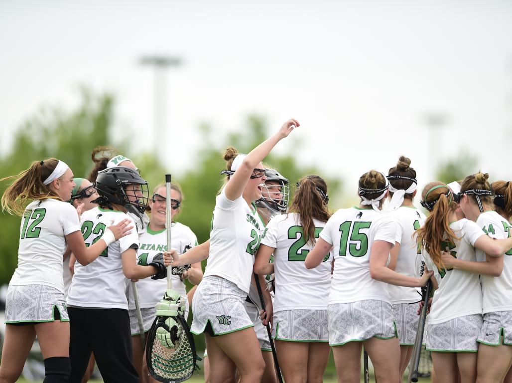 The York College Women's Lacrosse team huddled in a victory celebration.