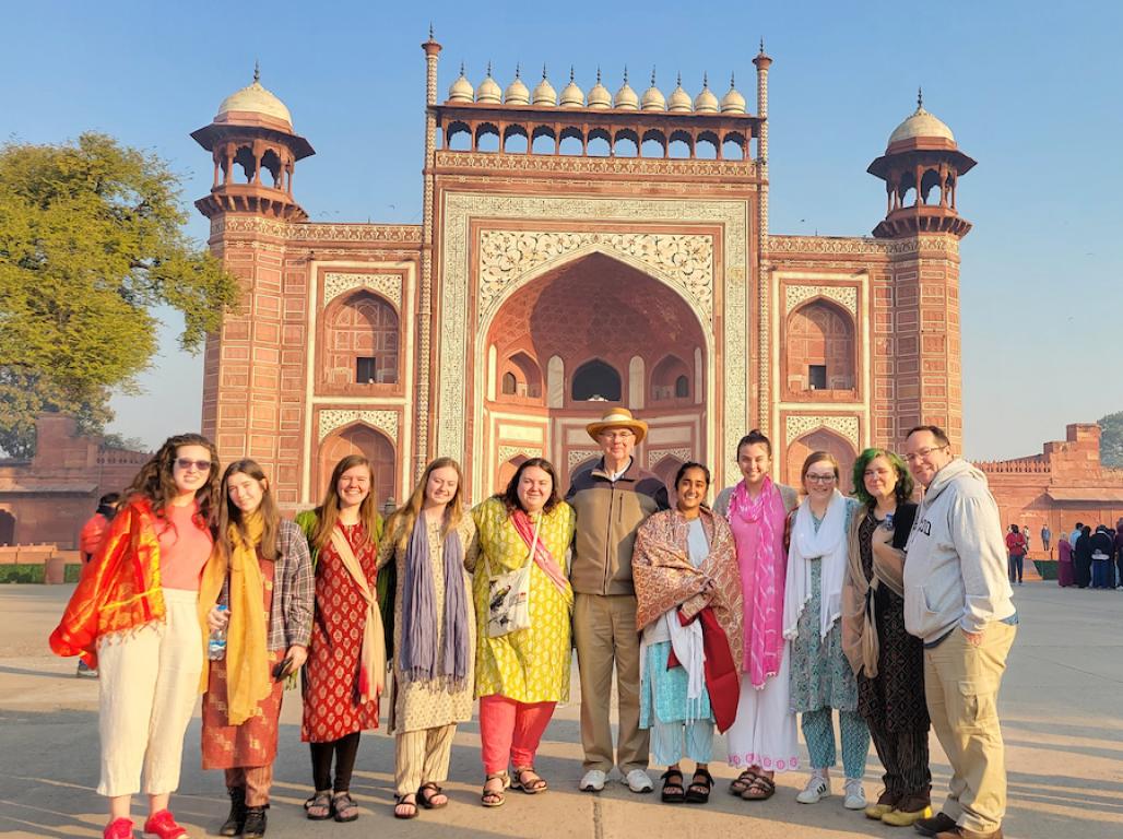 A group of eleven students and chaperones, many dressed in traditional Indian clothing, pose for a group photo on a study abroad trip to India.