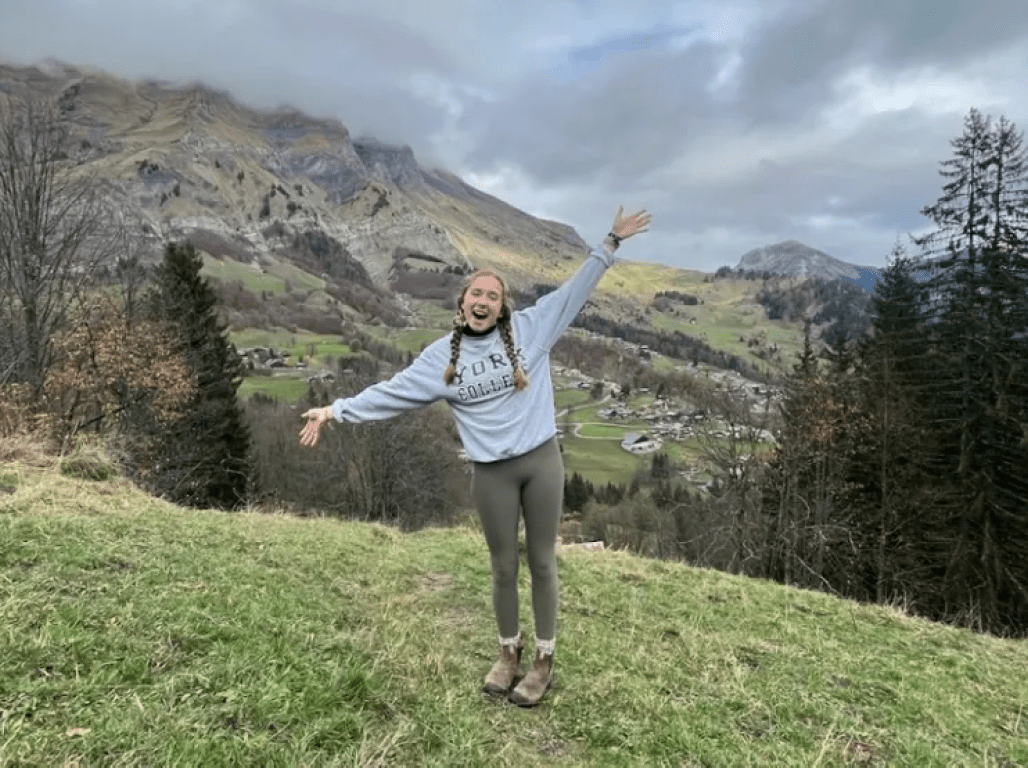 Abby Wurzbach stretches her arms wide and smiles at the top of a European hillside on an overcast day.