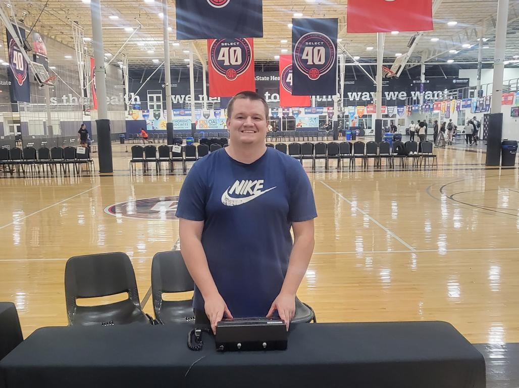 Austin Brown standing behind a table holding an electronic control device.