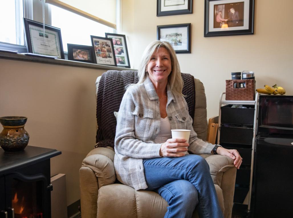 Barb Hanbury in her office space holding a cup of coffee.