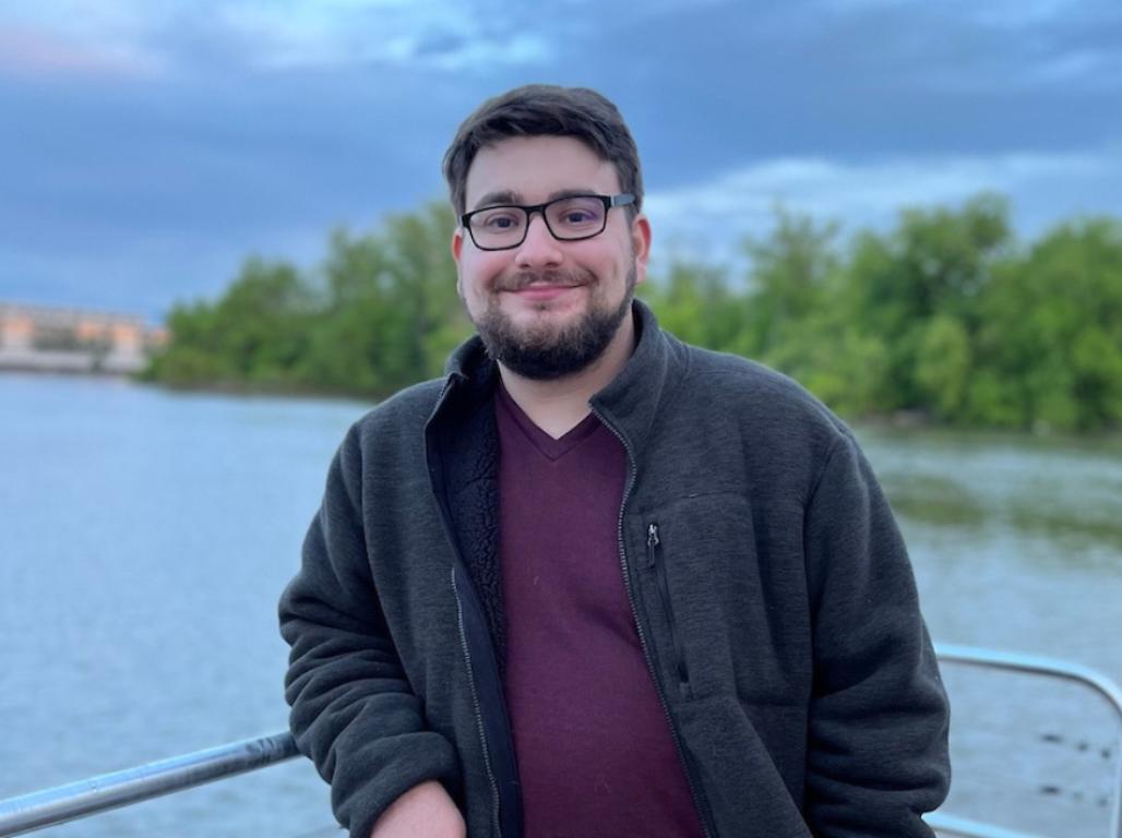 Brian Levy stands leaning on the rail of a boat in a lake.