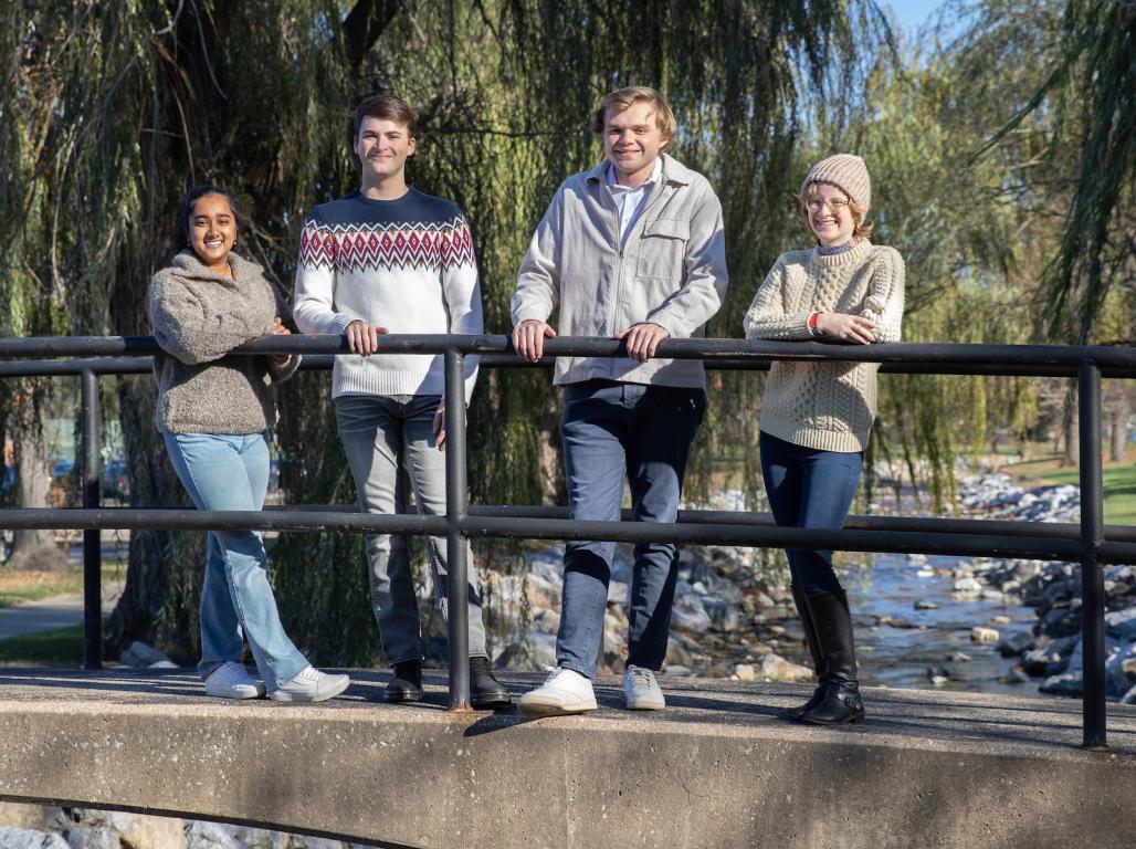 Four students gather on a footbridge over the Tyler Run Creek.