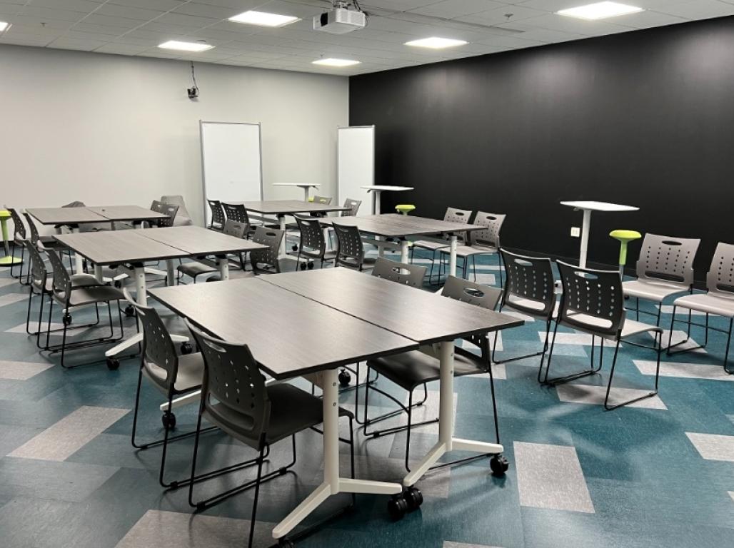 The Innovation Classroom showing four person tables and a chalkboard wall