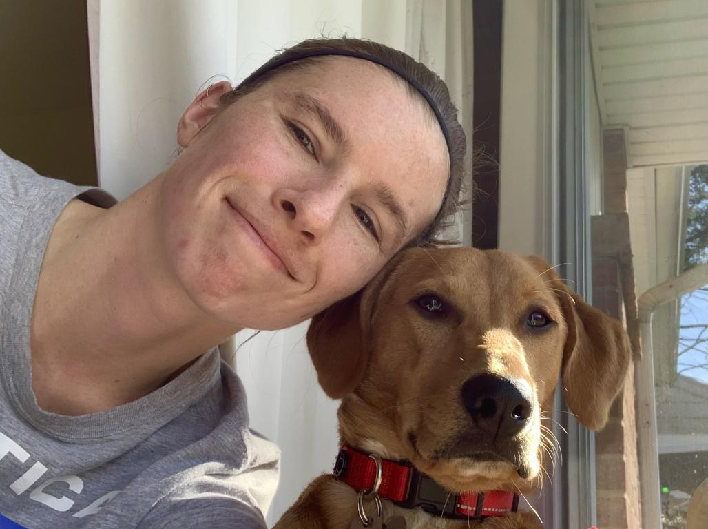 Jennifer Hindley smiling and leaning head to head with her dog.