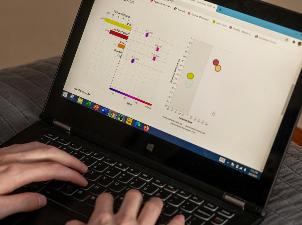 Hands type on a laptop with a close-up on the screen showing data and charts.