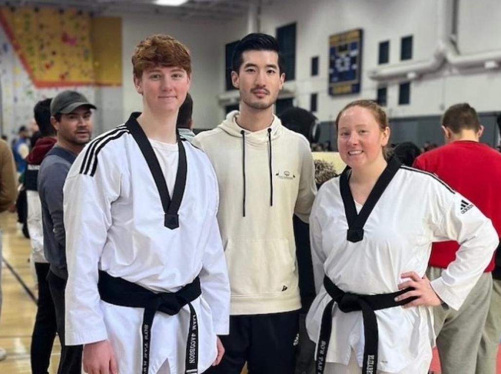 Elizabeth Jacobson and Liam Jacobson in uniform pose with their Taekwondo instructor, Derek So. 