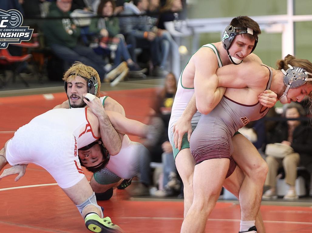 Two pairs or student wrestlers grapple during a match. 