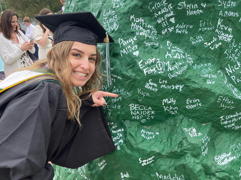 Kya Moul pointing at her name on the rock that she signed.