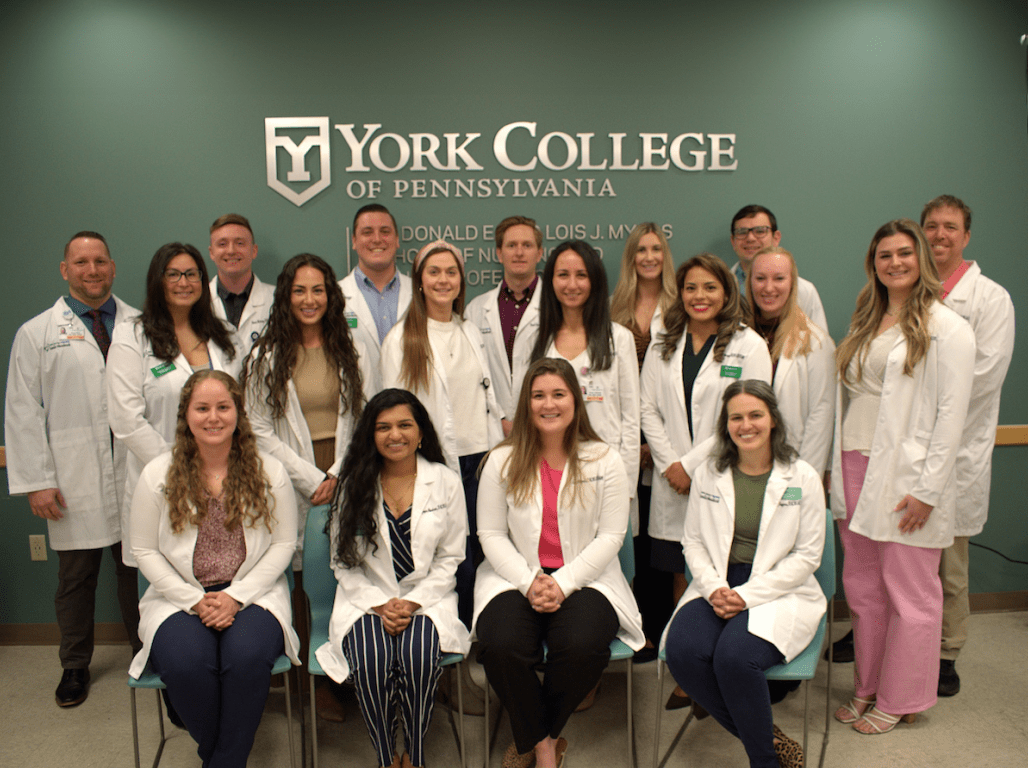 A group of graduates from the DNP Nurse Anesthetist program pose for a group photo in their white coats.