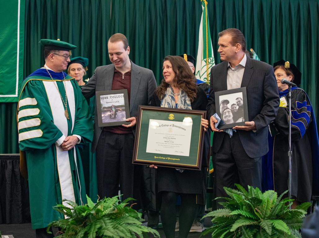 Dr. Burns and Tristan Shilling's family standing with Tristan's framed diploma.