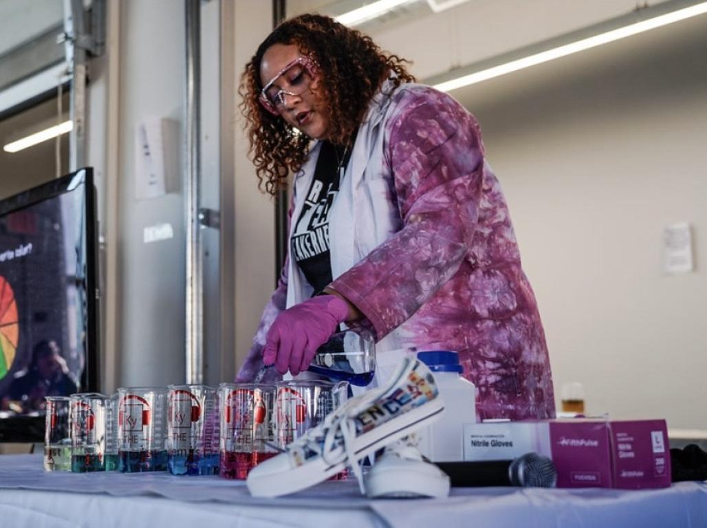 Jakyra Simpson, a.k.a. Ky the Chemist is poring colored liquid into a beaker.