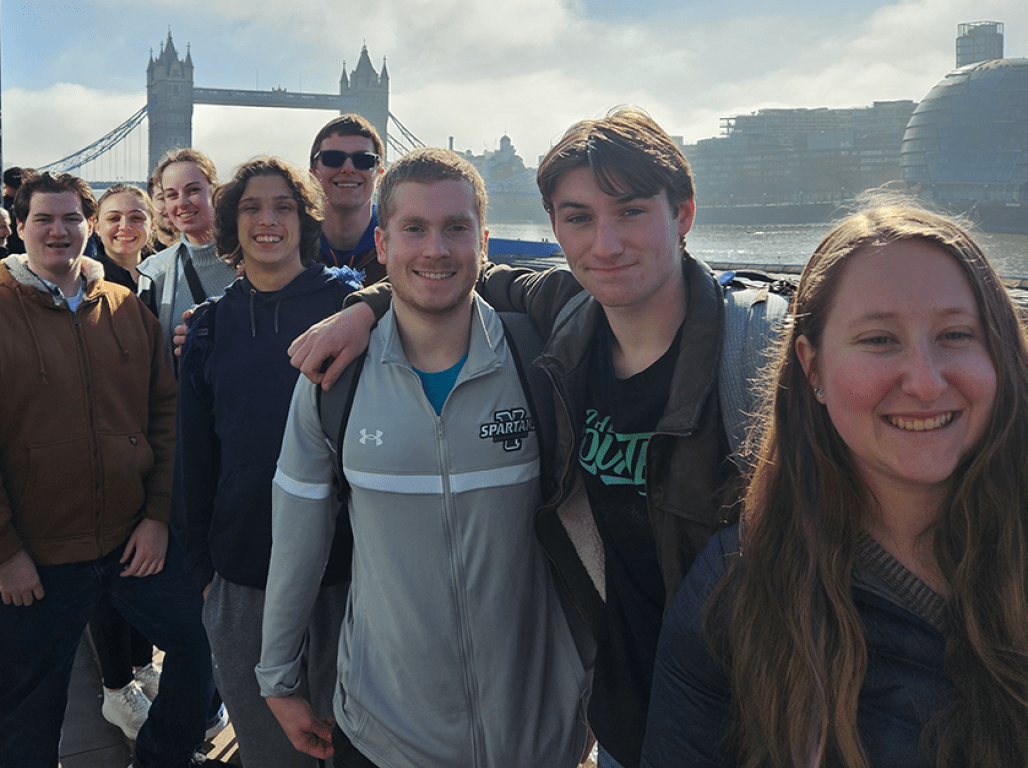 A group of students pose for a photo in front of the London Bridge.