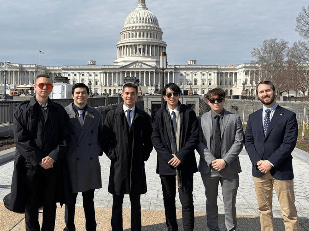 People in professional attire standing in front of the United States Capitol Building in Washington D.C.