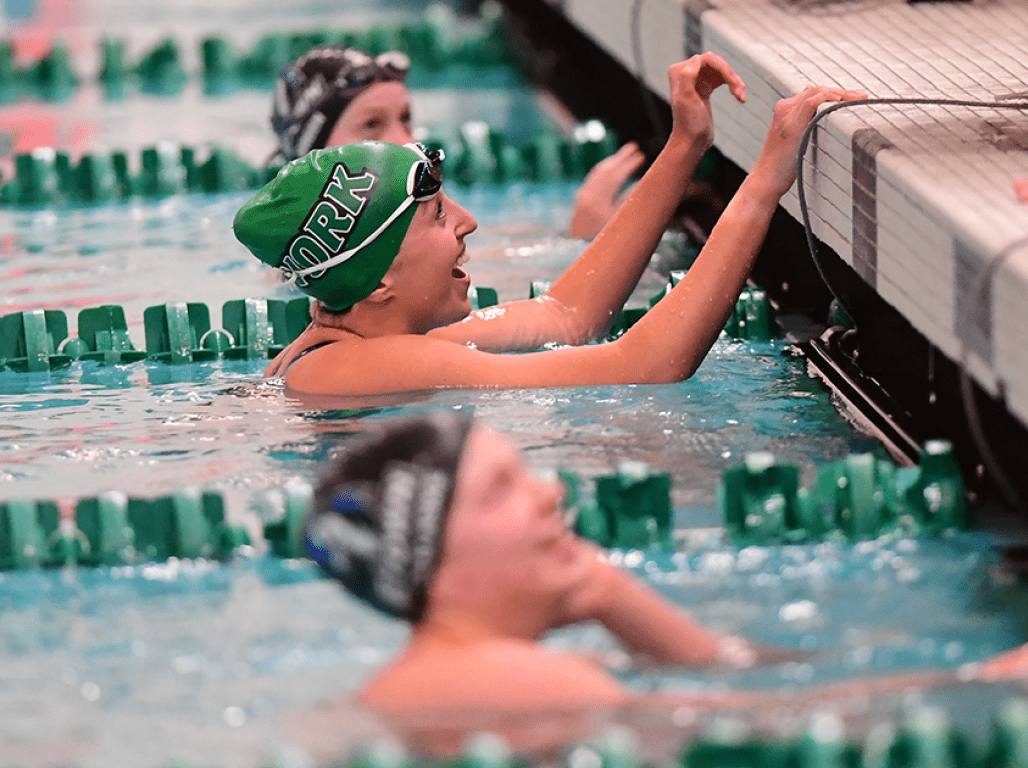 Members of the swim team smile in the water before the next heat.