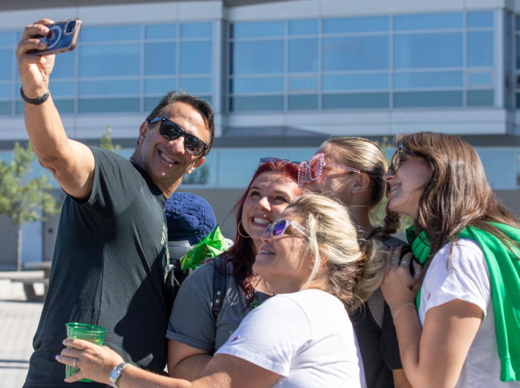 A group of people pose for a selfie outside on a sunny day.