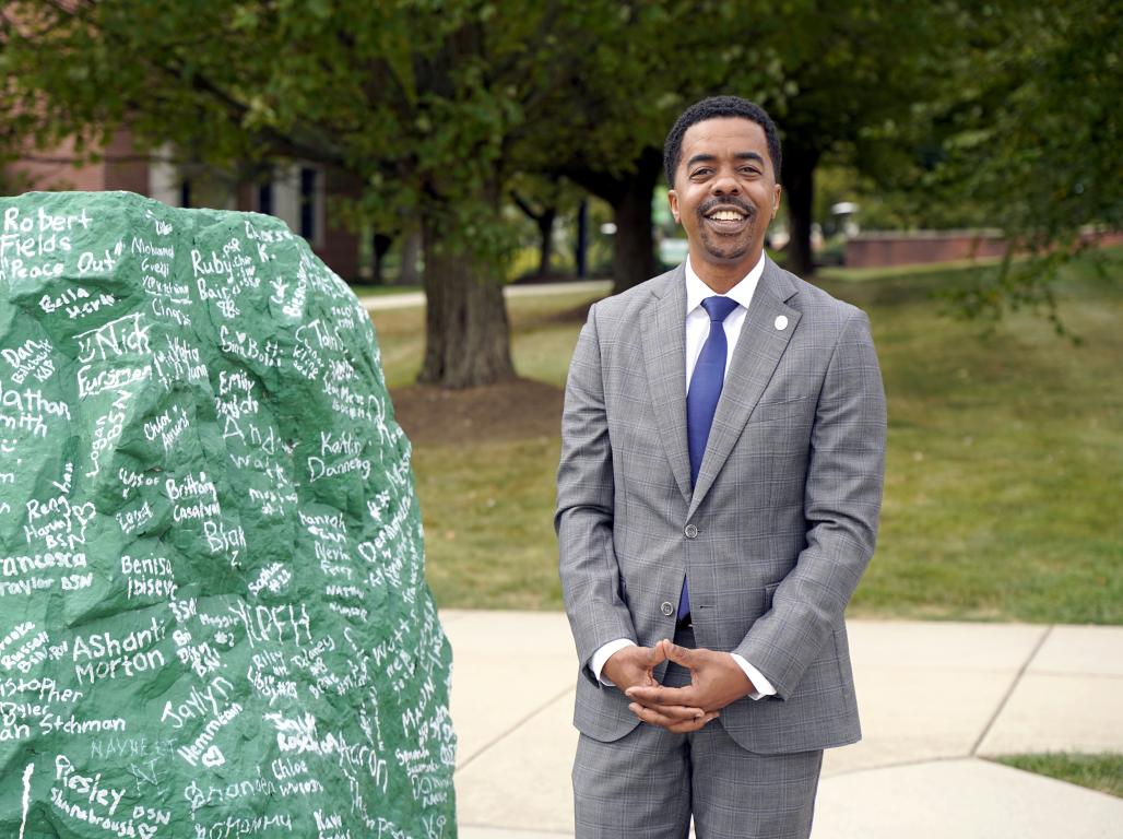 York College CFO Michael Doweary stands next to a rock with signatures on it