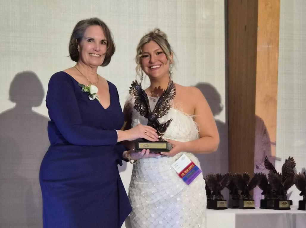 Associate Professor of Cybersecurity Dr. Tamara Schwartz accepting an award at a formal event.