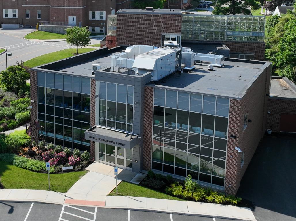 Aerial view of York College’s Appell Horticulture Center, including surrounding landscaped gardens, campus buildings, trees, and parking areas.