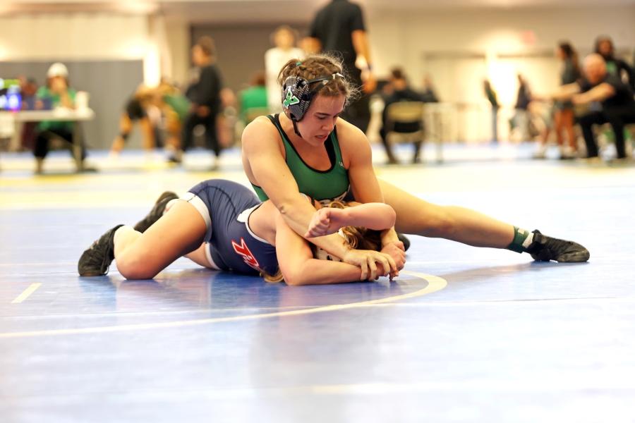 Two students are wrestling. One student has the other in a hold on the mat.