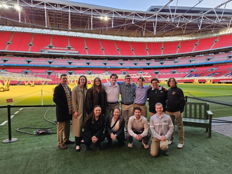 A group of individuals pose for a photo inside a sports stadium.