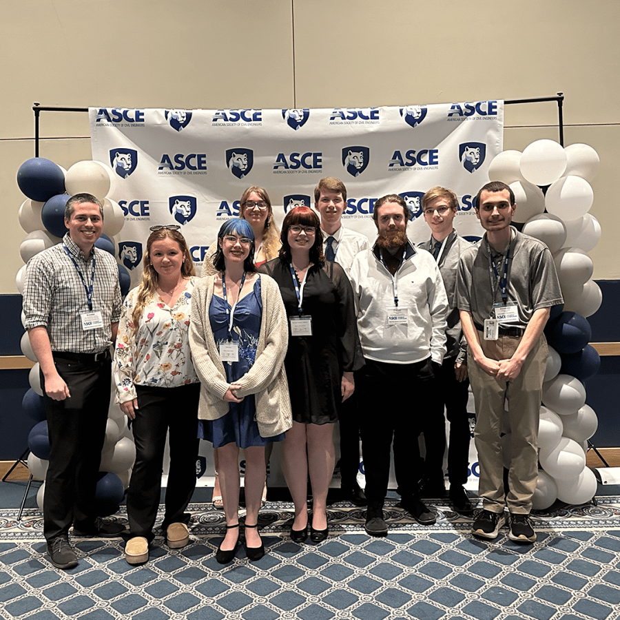 A group of engineering students wearing professional attire stands in front of an ASCE backdrop with festive blue and white balloons on either side.