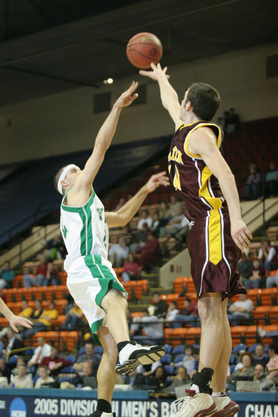 Two basketball players competing for control of the ball in an indoor basketball court setting.
