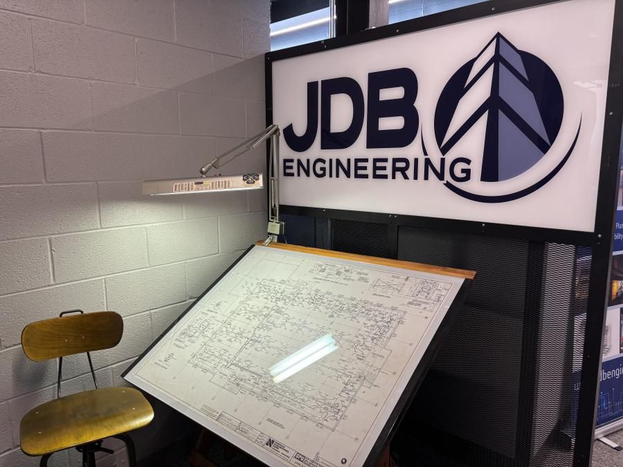 A chair and desk with a large JDB Engineering sign above the desk