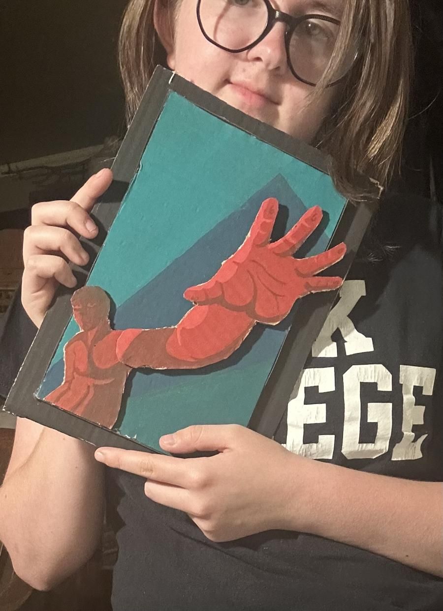 Student Aeris Brewer holding an art piece depicting a human figure reaching their hand out.
