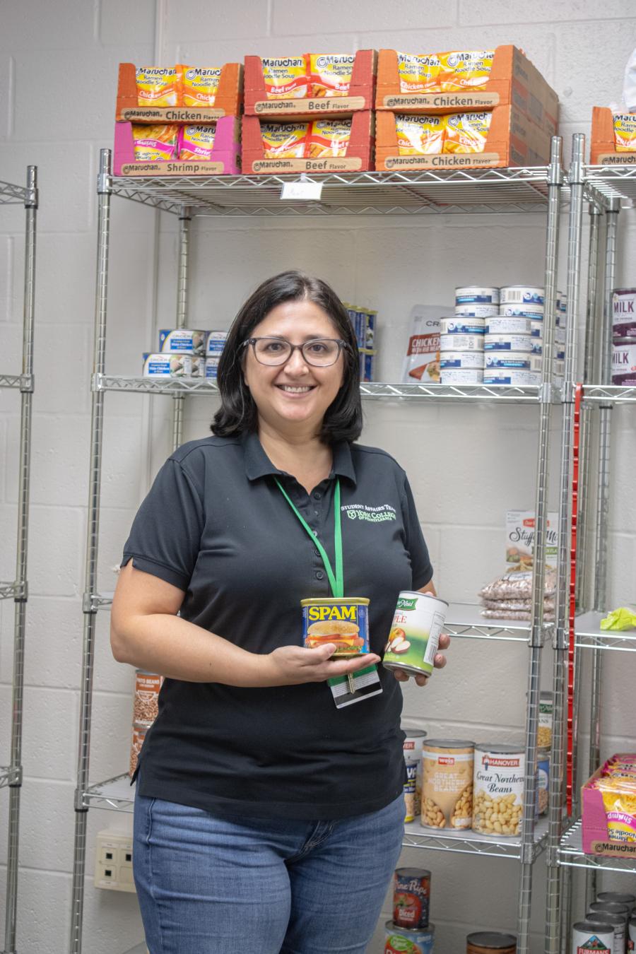 Ines Ramírez standing in the Spartan Food Pantry, showcasing some items.